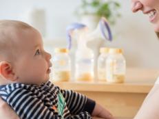 Caucasian woman holding baby son near bottles of breast milk