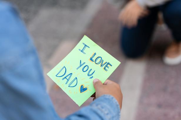Unrecognizable little boy holding a father's day card written in english - Celebration concepts