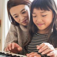 Mother teaching daughter with an electronic piano