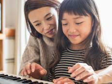 Mother teaching daughter with an electronic piano