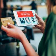 Young woman sitting in a cafe and holding credit card and digital tablet