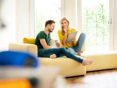 Couple sitting on couch in their new home, using digital tablet
