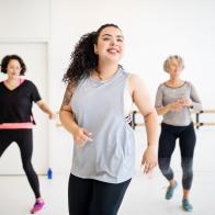 Young woman learning dance moves in fitness class. Multi-ethnic women dancing in studio.