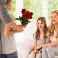 Father and son surprising mother and daughter with red roses.