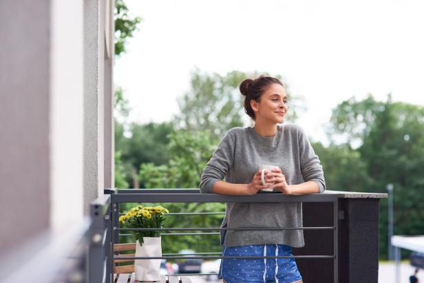Young woman drinking morning coffee on the balcony
