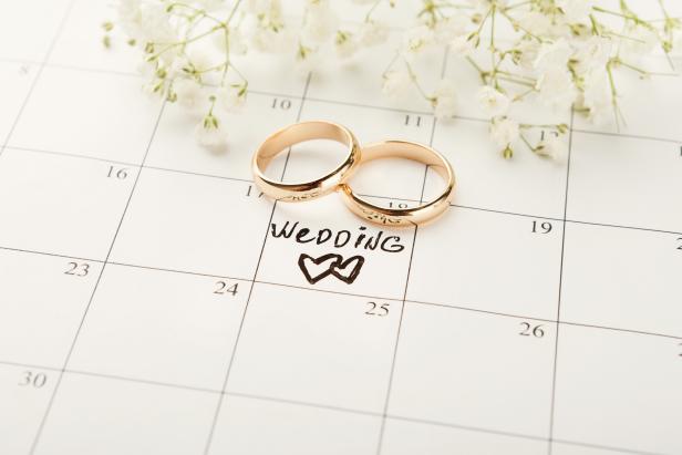 Word wedding, two hearts and gold rings on calendar with sweet white flowers. Love, invitation, advertisement, romantic background concept