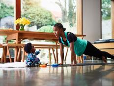 Baby boy (6-11 months) assisting mother performing yoga in livingroom
