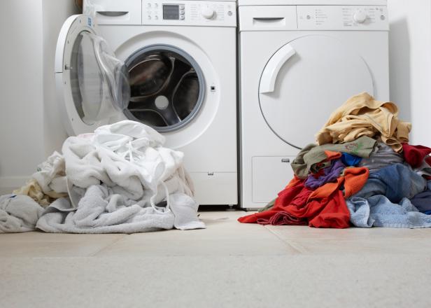 An image of a washing machine and a pile of white and colored clothes