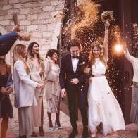 Newlywed bride and groom leaving church and celebrating wedding with guests throwing flowers and rice