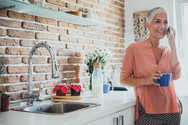 Older Caucasian woman talking on cell phone in kitchen