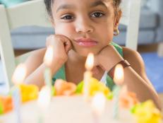 African American girl pouting at birthday cake