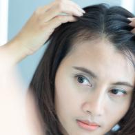 Woman looking reflection in the mirror serious hair loss problem for health care shampoo and beauty product concept