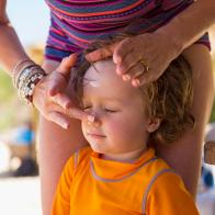 Caucasian mother applying sunscreen to face of son