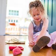 Caucasian girl sitting on floor fastening sandal