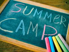 text summer camp written with chalk on a chalkboard, and some chalk sticks of different colors