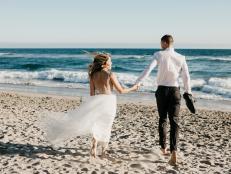 Rear view of bride and groom running on the beach