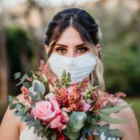 Bride Smiling behind the mask with bouquet of flowers in hand