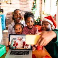 Close up of a young family taking a selfie with Santa on a Video call on their laptop