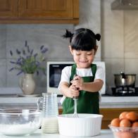 child girl enjoy cooking in the kitchen. Happy Asian kid is preparing the dough, bake cookies in the kitchen.