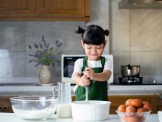 child girl enjoy cooking in the kitchen. Happy Asian kid is preparing the dough, bake cookies in the kitchen.