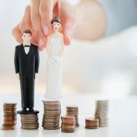 Mixed race woman balancing bride and groom statues on coin stacks