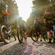 Low angle perspective of multi-ethnic family with mountain and gravel bikes on dirt road in forest.  North Vancouver, British Columbia, Canada.