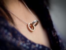 A necklace with two joined rings, representing friendship or love. Very romantic, shallow focus with other elements blurred out creatively.  Gold and Silver.