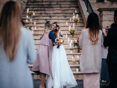 Loving mother embracing elegant bride at outdoors rustic cottage wedding ceremony in Europe