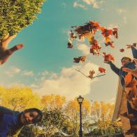 Children playing with plane tree autumn leafs in the home backyard with nice action moment. With the picture taken with adult laying on the leafs from personal point of view.