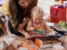 Child unwrapping presents with help from her mother at first birthday party