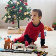 Cute little boy, playing with toys at Christmas at home, early morning, child still in pajama after unwrapping presents.