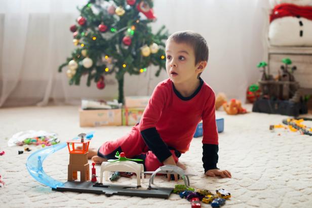 Cute little boy, playing with toys at Christmas at home, early morning, child still in pajama after unwrapping presents.