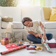 Black woman sitting on floor wrapping gifts