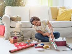 Black woman sitting on floor wrapping gifts