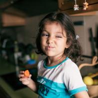 Pretty 4 years girl eating carrot in kitchen, sitting on her kitchen counter