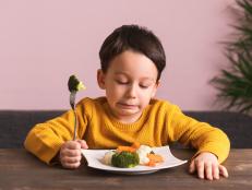 Child is very unhappy with having to eat vegetables. There is a lot of vegetables on his plate. He hates vegetables.