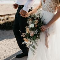 Close-up of bride and groom walking on path at the coast