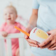 Selective focus of mother holding baby monitor near daughter at background