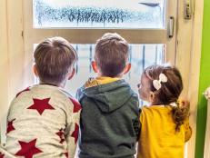 Back view of small group of children enjoying winter holidays, looking through the window.