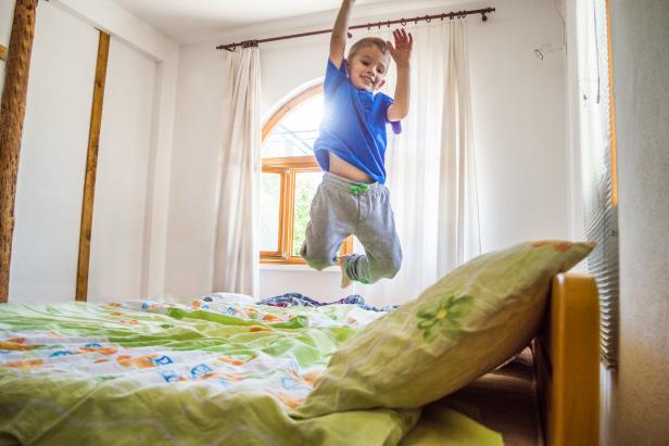 Little boy is jumping on the bed. He is flying!