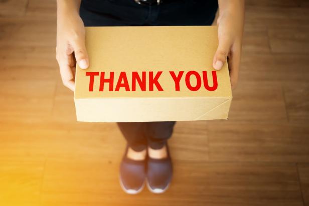 Thank you message for customer who shopping with your shop concept : Thank you message word on simple delivery brown box in hand of friendly sender man