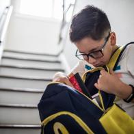 School age boy looking through backpack