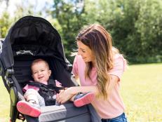 A Portrait of beautiful young woman pushing baby carriage in the park