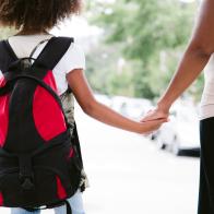 african american mom and daughter hold hands while walking