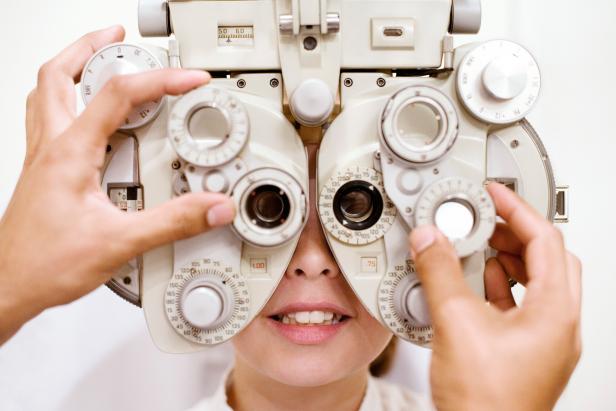 Eye examination. Optician using a phoropter to examine a ten year old girl's eyes. This device is used to measure the refractive error in the eyes and to determine an individual's lens prescription. A refractive error is an error in the focusing of light by the eye, which is one of the causes of visual sharpness.