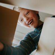 Happy young box opening a cardboard box and reaching in. Conceptual with space for copy.