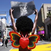 LOS ANGELES, CALIFORNIA  - JUNE 14: A protester strikes a pose while holding a 'Black Lives Matter' sign on Hollywood Boulevard during the All Black Lives Matter solidarity march, replacing the annual gay pride celebration, as protests continue in the wake of George Floydâ  s death on June 14, 2020 in Los Angeles, California. Organizers intend to â  amplify Black Queer voices and come together in solidarityâ   with the march. George Floyd died on May 25th when he was in Minneapolis police custody, sparking nationwide protests. A white police officer, Derek Chauvin, has been charged with second-degree murder, with the three other officers involved facing other charges.  (Photo by Mario Tama/Mario Tama/Getty Images)