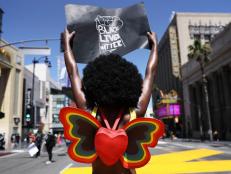 LOS ANGELES, CALIFORNIA  - JUNE 14: A protester strikes a pose while holding a 'Black Lives Matter' sign on Hollywood Boulevard during the All Black Lives Matter solidarity march, replacing the annual gay pride celebration, as protests continue in the wake of George Floydâ  s death on June 14, 2020 in Los Angeles, California. Organizers intend to â  amplify Black Queer voices and come together in solidarityâ   with the march. George Floyd died on May 25th when he was in Minneapolis police custody, sparking nationwide protests. A white police officer, Derek Chauvin, has been charged with second-degree murder, with the three other officers involved facing other charges.  (Photo by Mario Tama/Mario Tama/Getty Images)