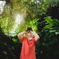 a boy looking in binoculars outdoors