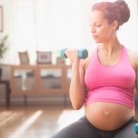 Pregnant mixed race woman exercising with dumbbells